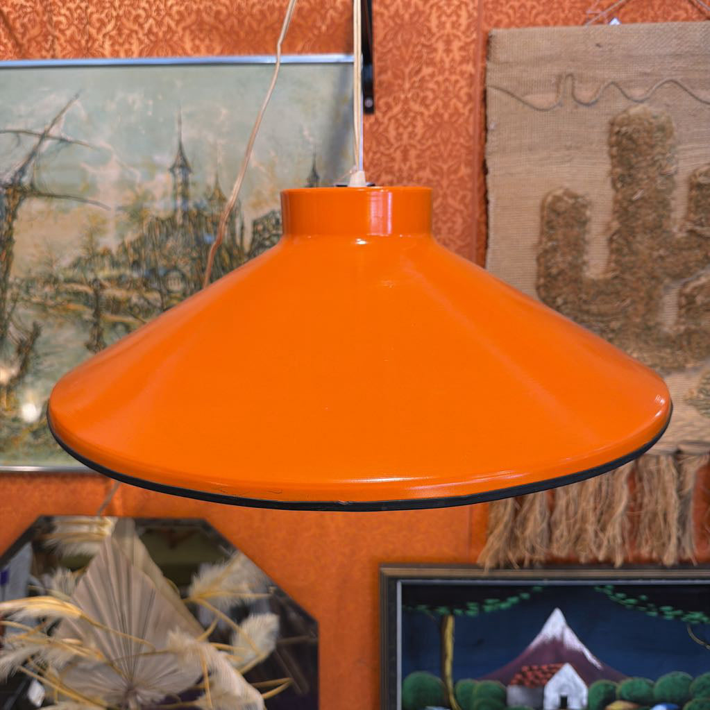 Orange lampshade with a blurred background of framed artworks