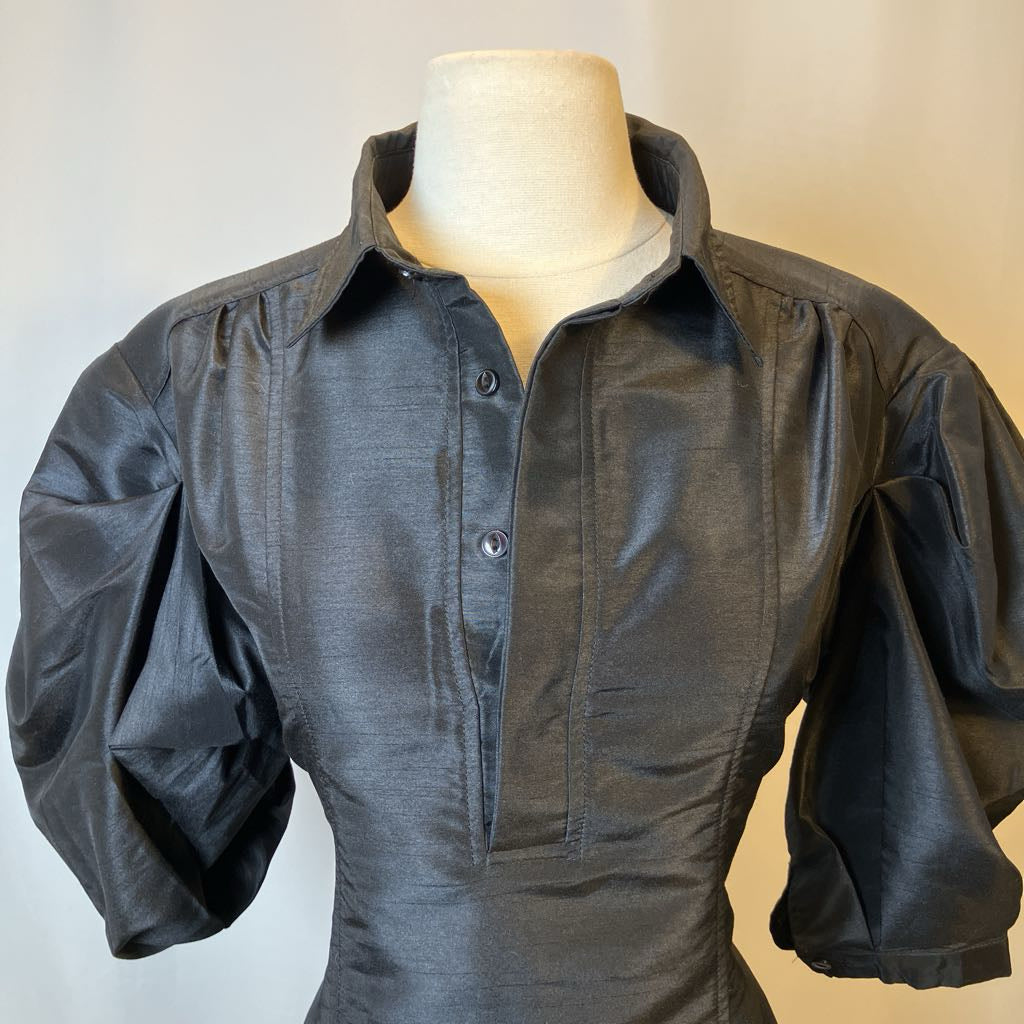 Dark black shirt on a mannequin against a plain background
