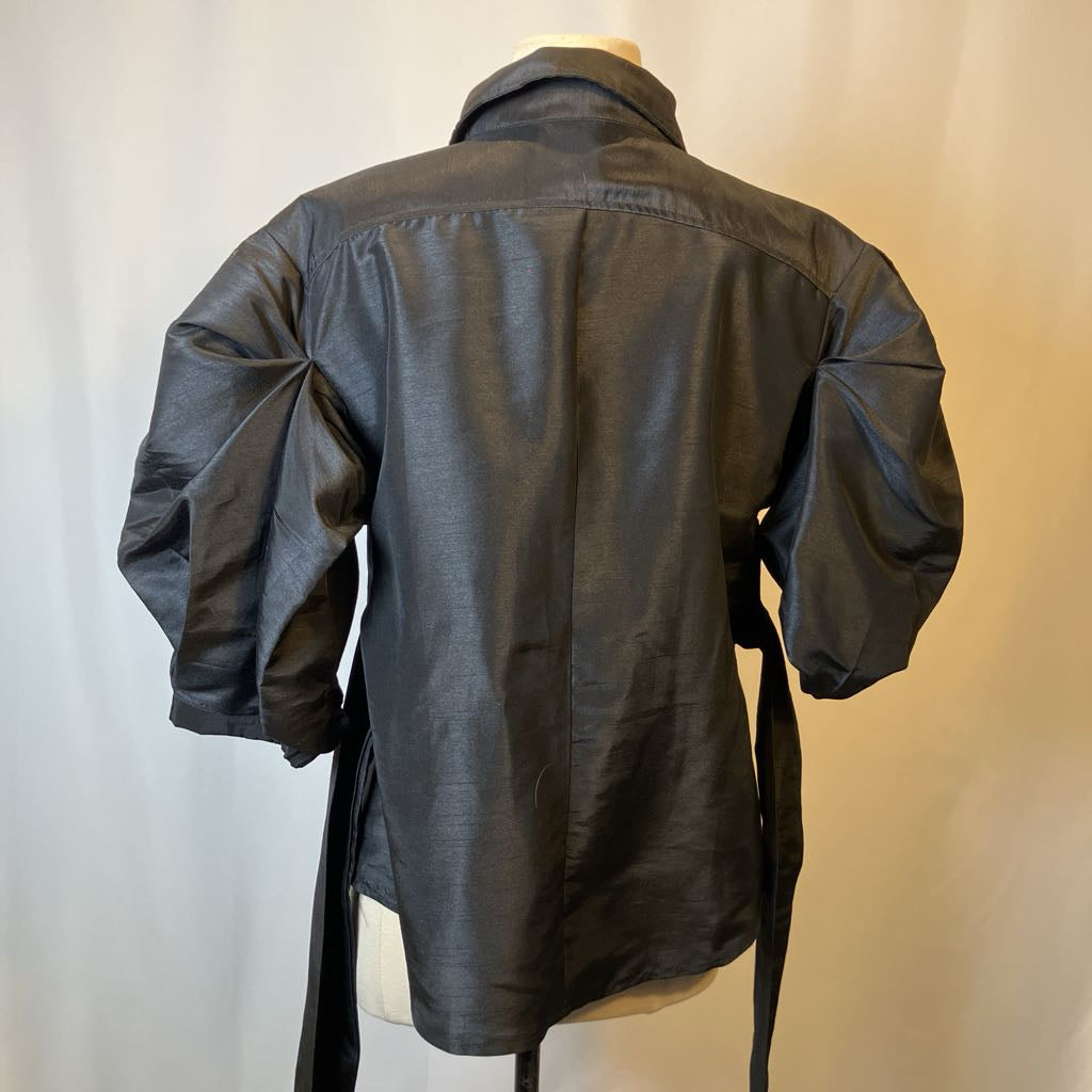 Black blouse on a mannequin against a plain background