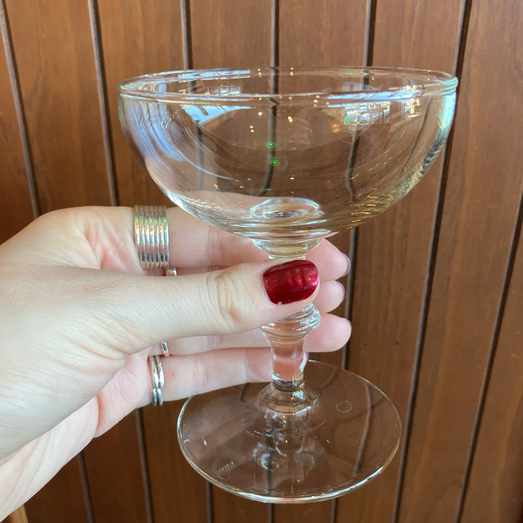 Clear glass held by a hand with red nail polish against a wooden background