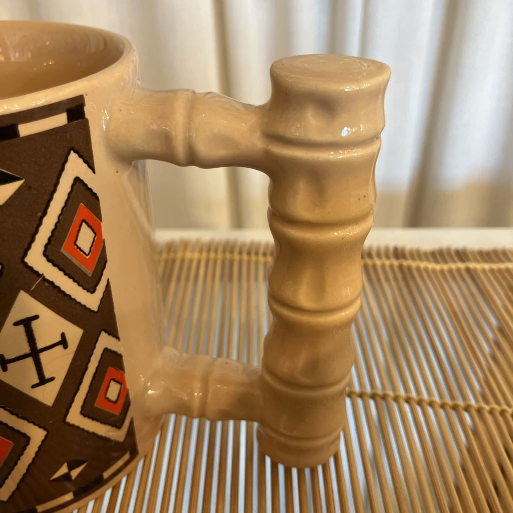 Ceramic mug with decorative handle on a woven surface