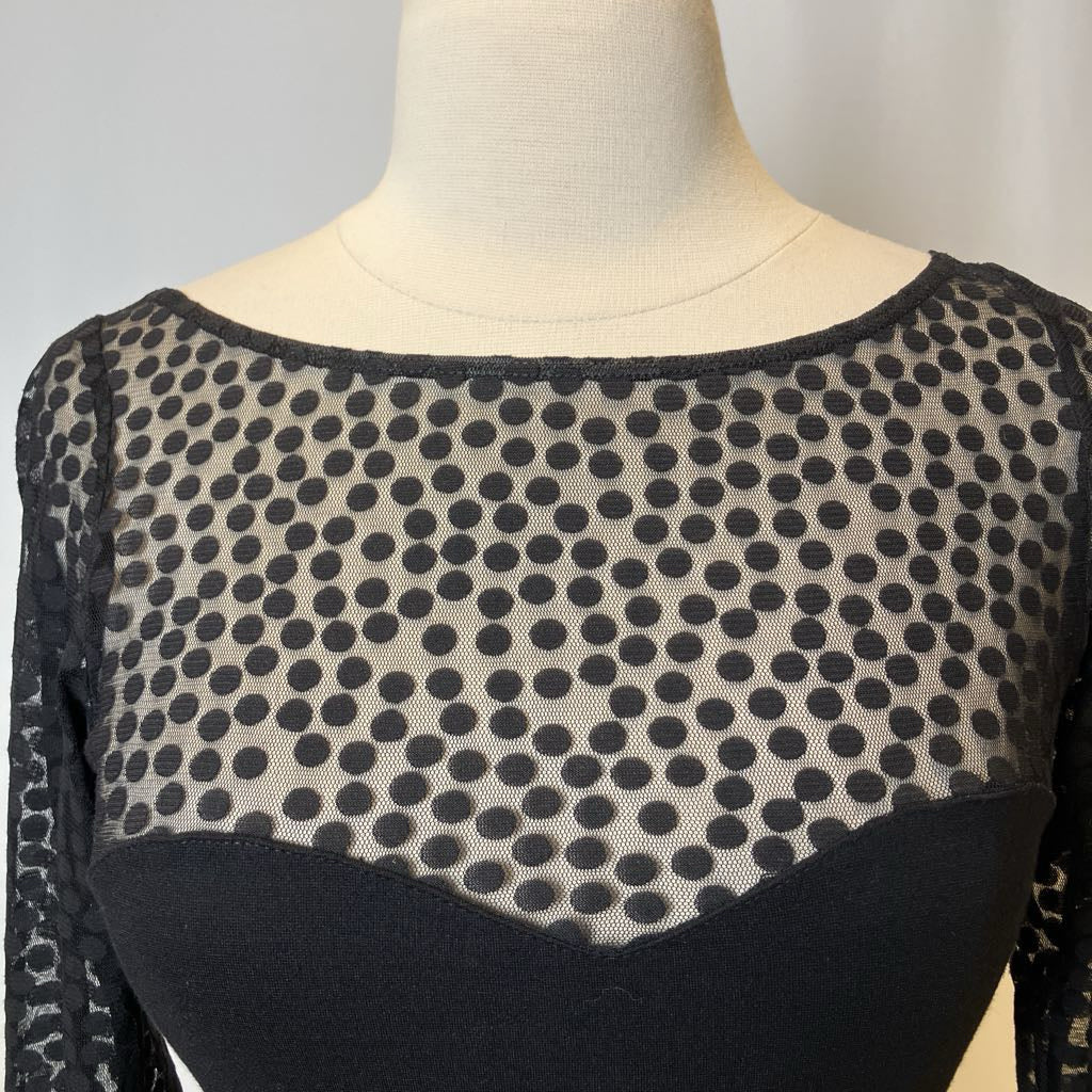 Mannequin wearing a black and beige polka dot top with a plain background