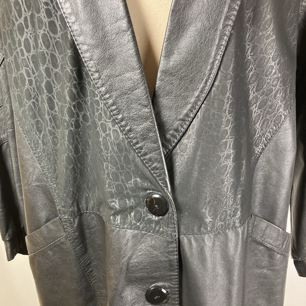 Close-up of a textured gray leather jacket with a button on a beige background