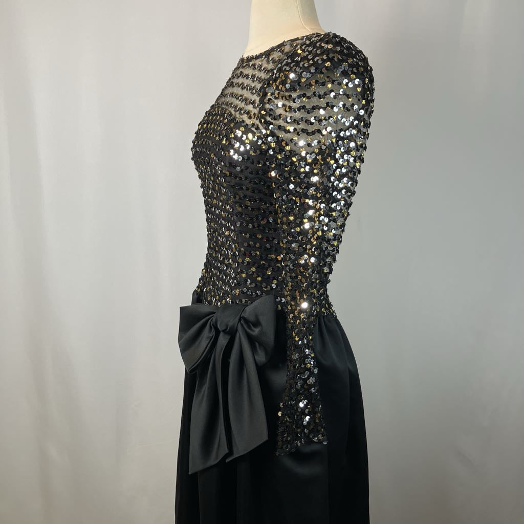 Black sequin dress with a large bow on a mannequin against a plain background