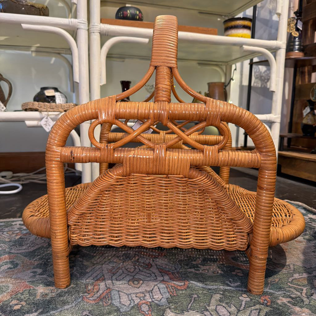 Wicker magazine rack on a patterned rug with a blurred background