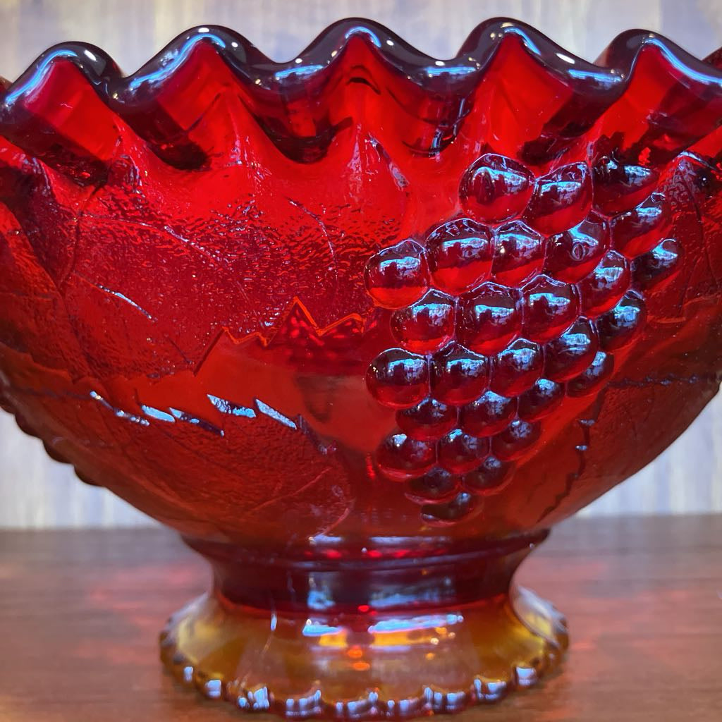 Red glass bowl with grape design on a wooden surface