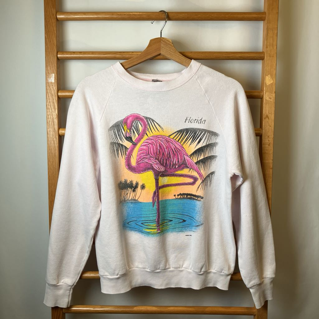 White sweatshirt with flamingo design on a wooden rack