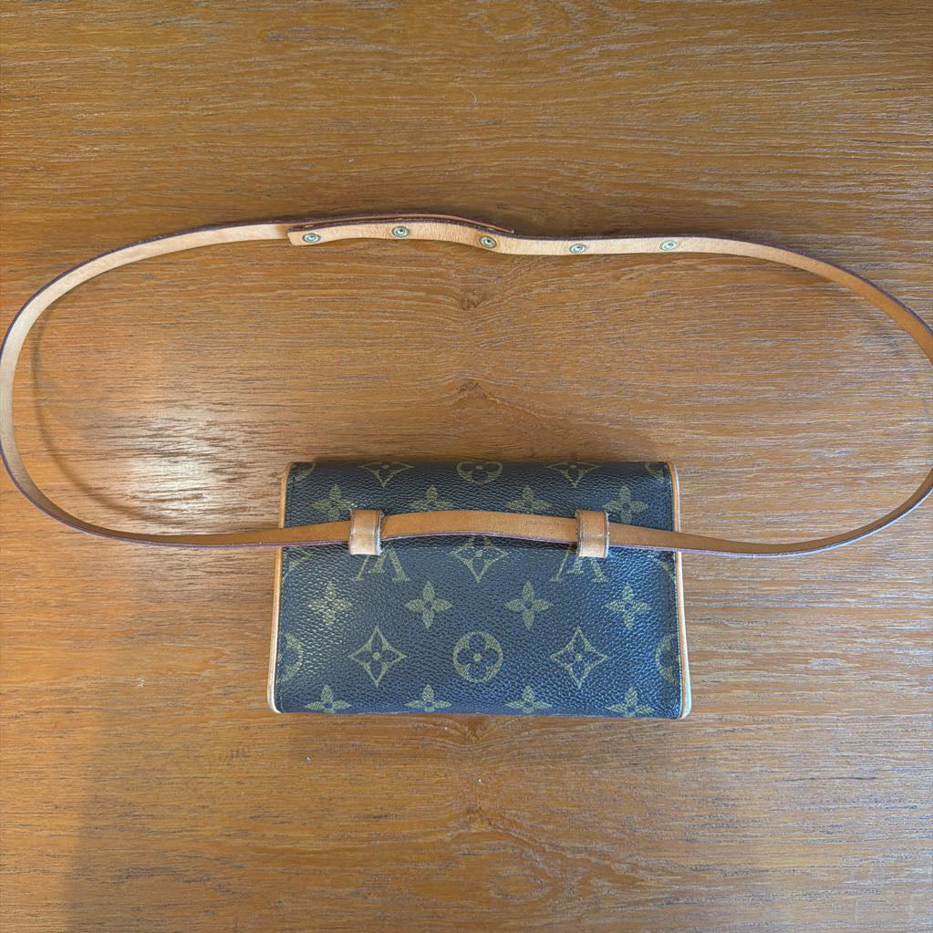 Blue handbag with brown strap on a wooden surface