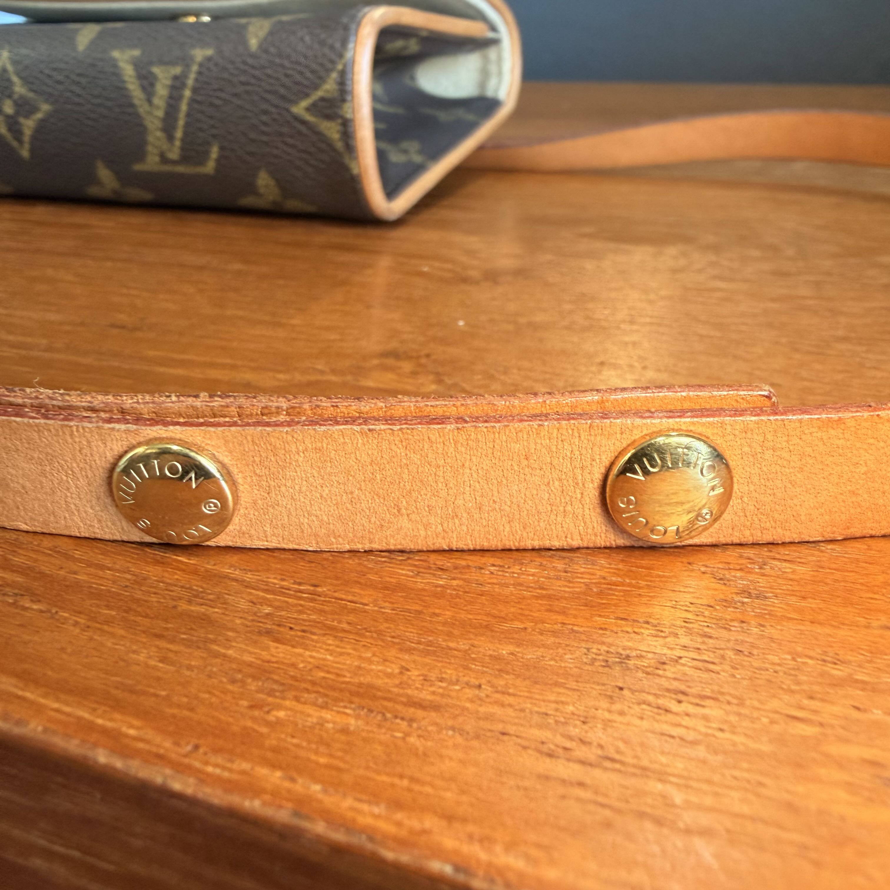 Close-up of a Louis Vuitton handbag with visible branding on a wooden surface.