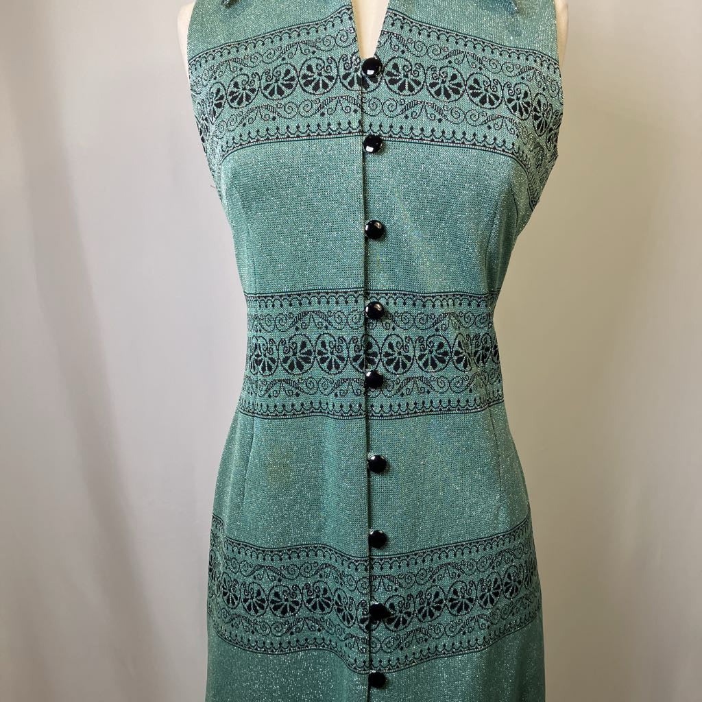 Green dress with black pattern and buttons on a plain background