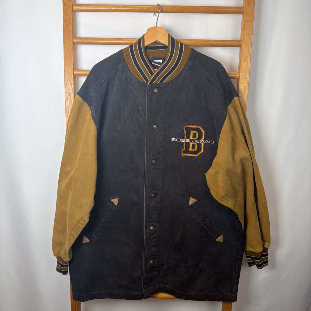 Black and tan letterman jacket with 'Boss Jeans' logo on a wooden rack.