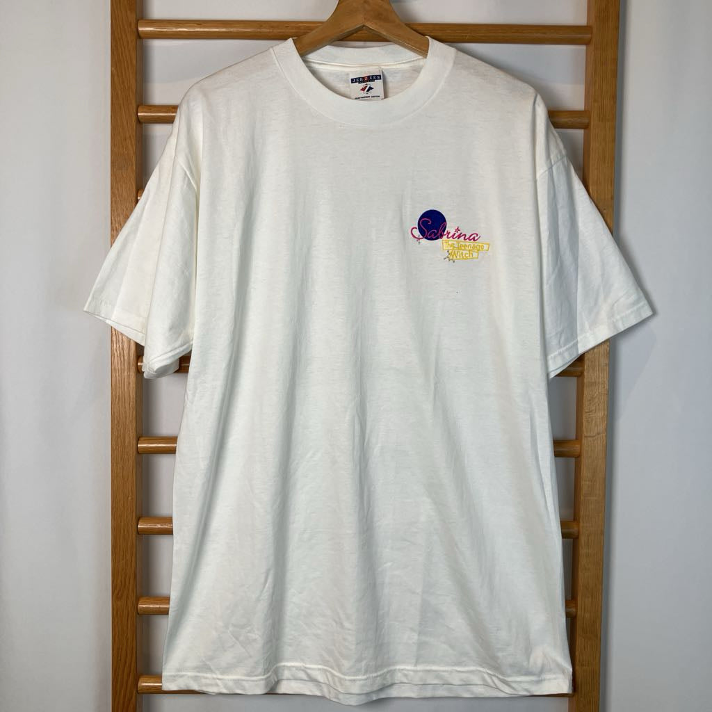 White t-shirt with a small graphic on a wooden hanger against a white wall