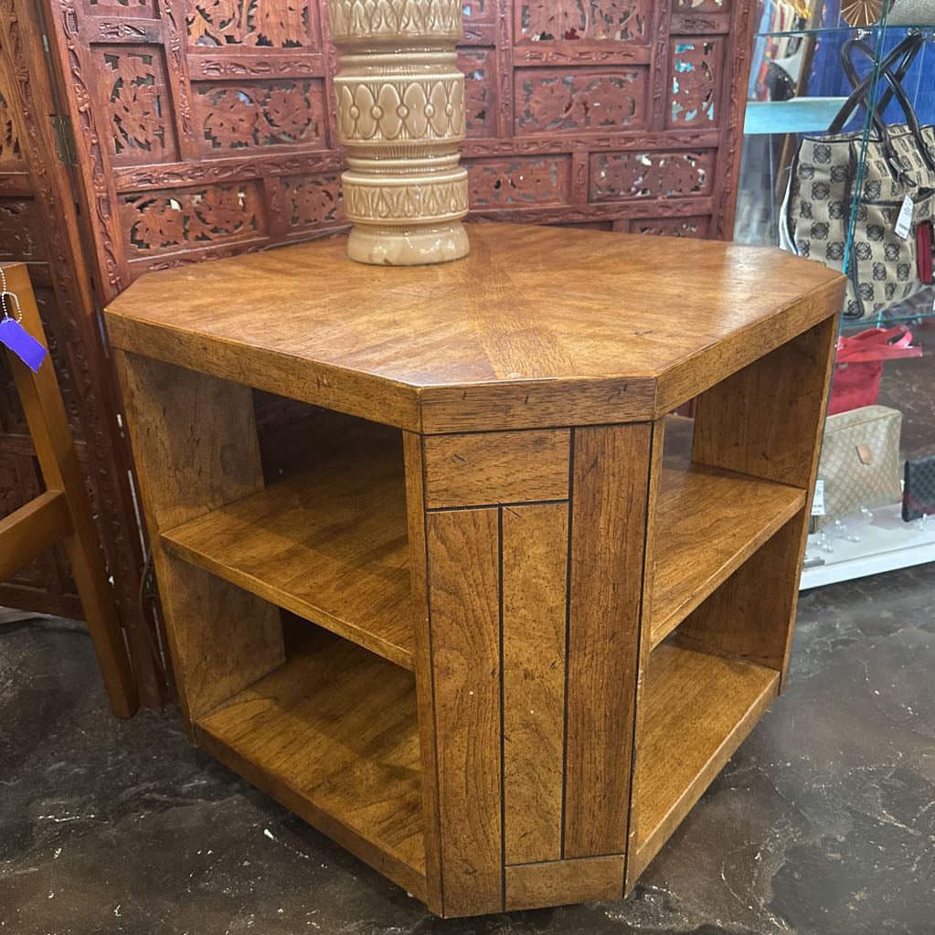 Brown wooden side table with shelves in a store setting.