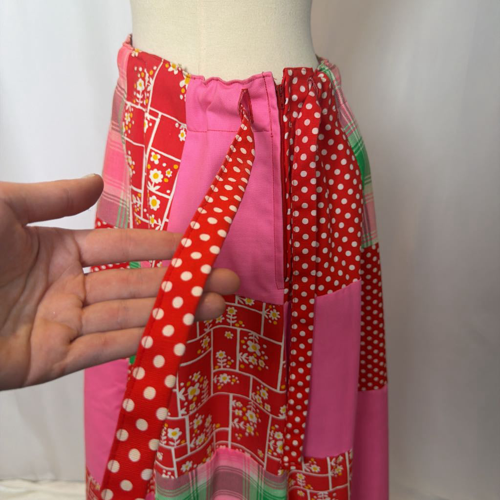 Colorful patchwork skirt on a mannequin with a hand adjusting it against a white background