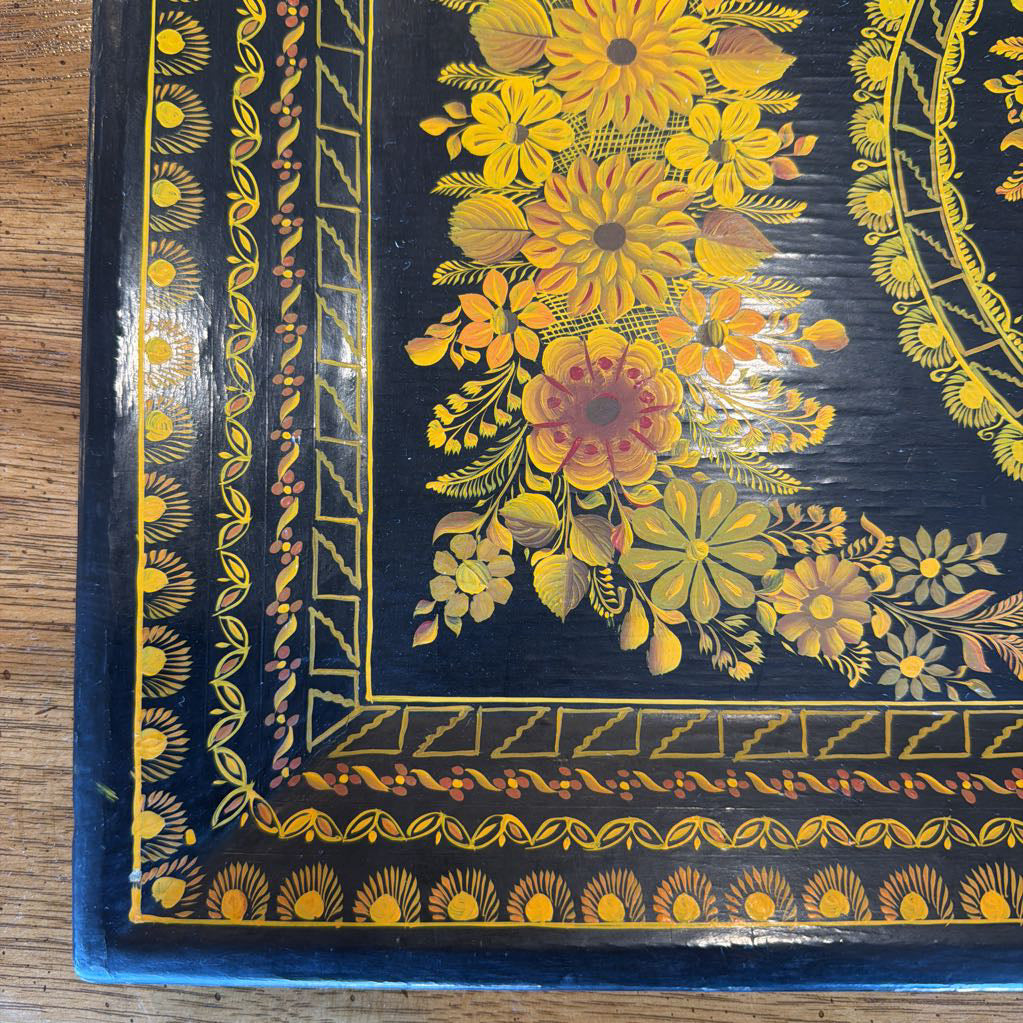 Decorative tray with floral patterns on a wooden surface
