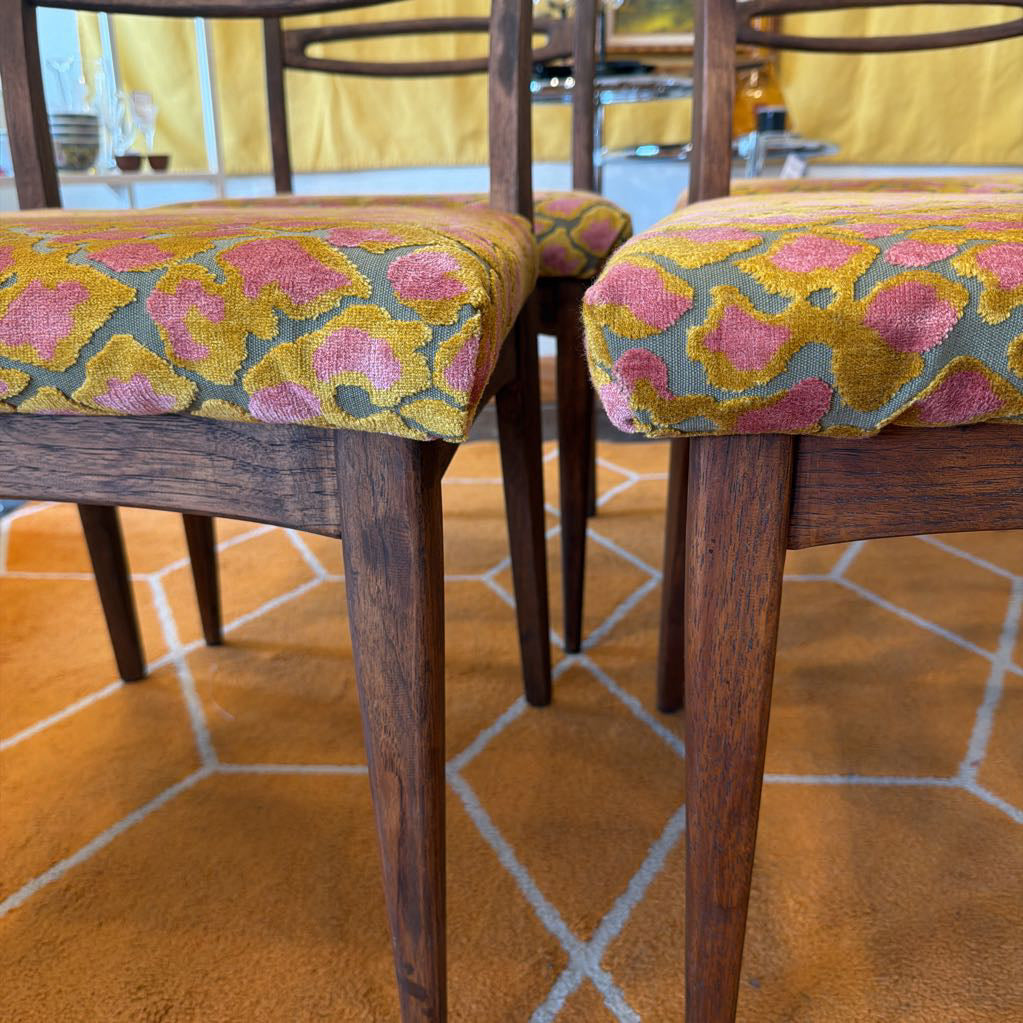 Wooden chairs with floral patterned cushions on a patterned rug.