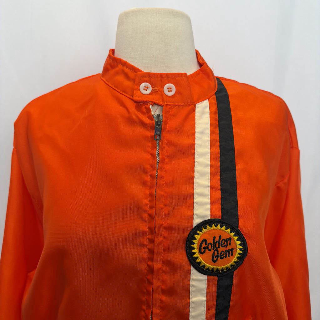 Orange jacket with a 'Golden Gem' patch on a mannequin against a white background