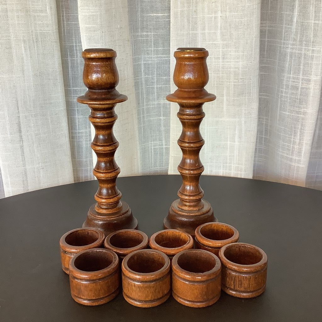 Set of wooden candle holders on a dark surface with a light curtain background