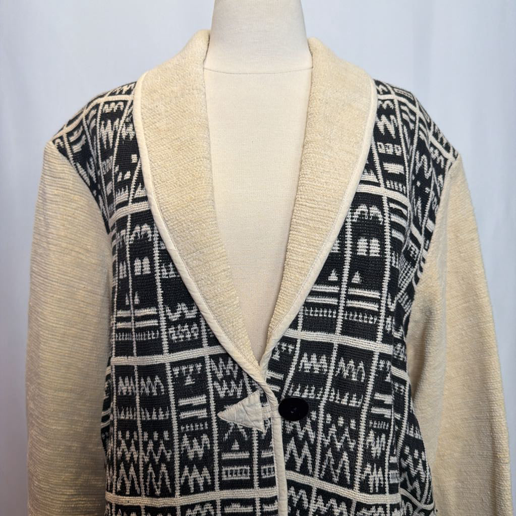 Mannequin wearing a patterned cardigan with a black and white geometric design on a light gray background
