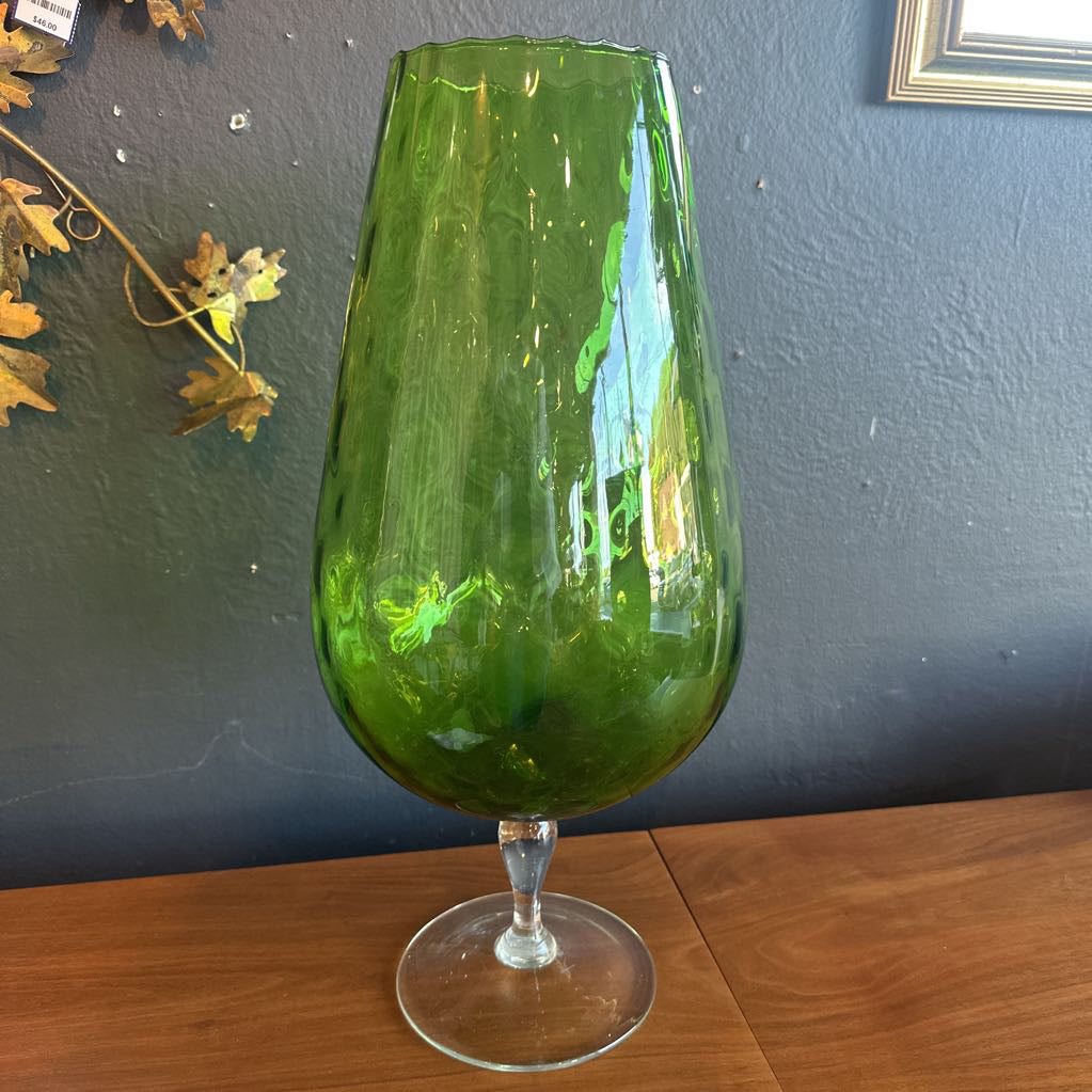 Green glass on a wooden surface with a blue wall in the background