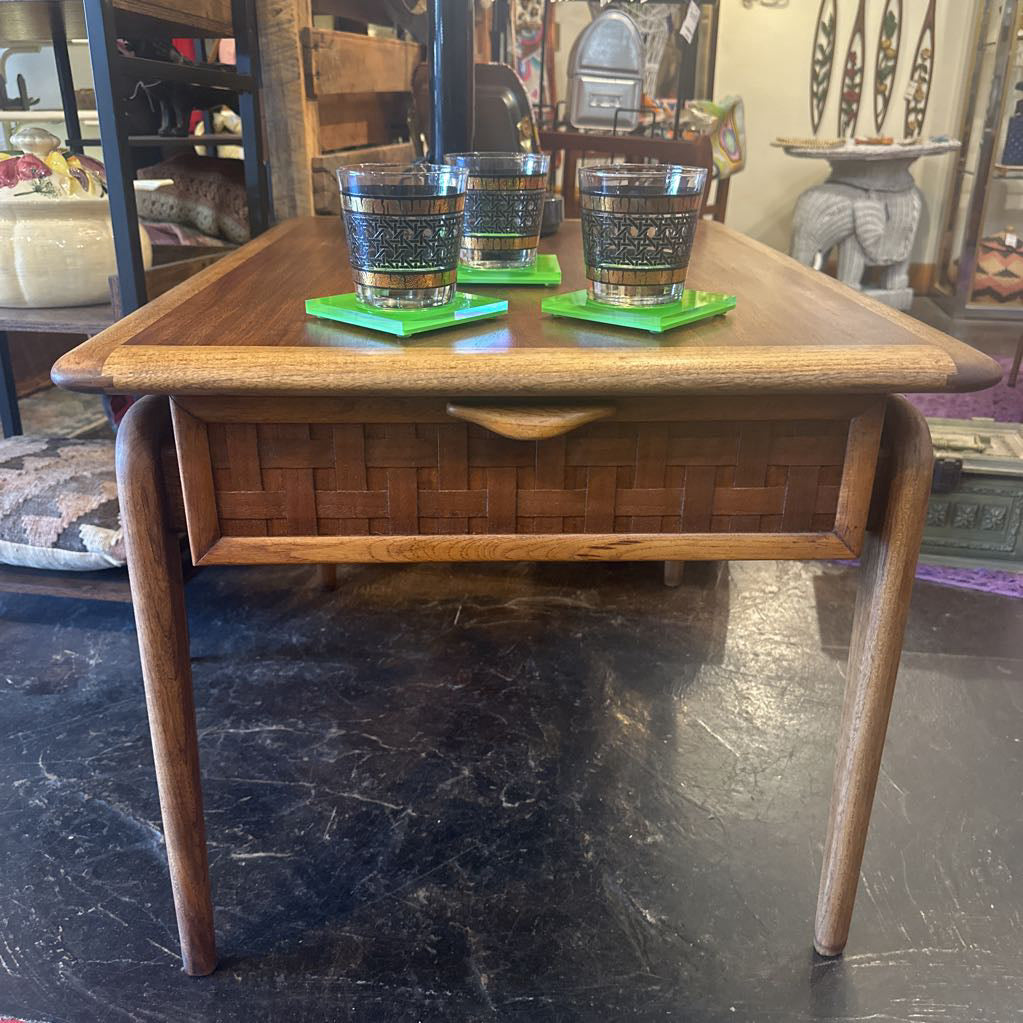 Wooden side table with two glasses on green coasters in a store setting