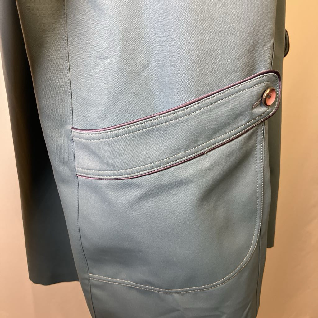 Close-up of a light gray suit jacket with a button on a beige background