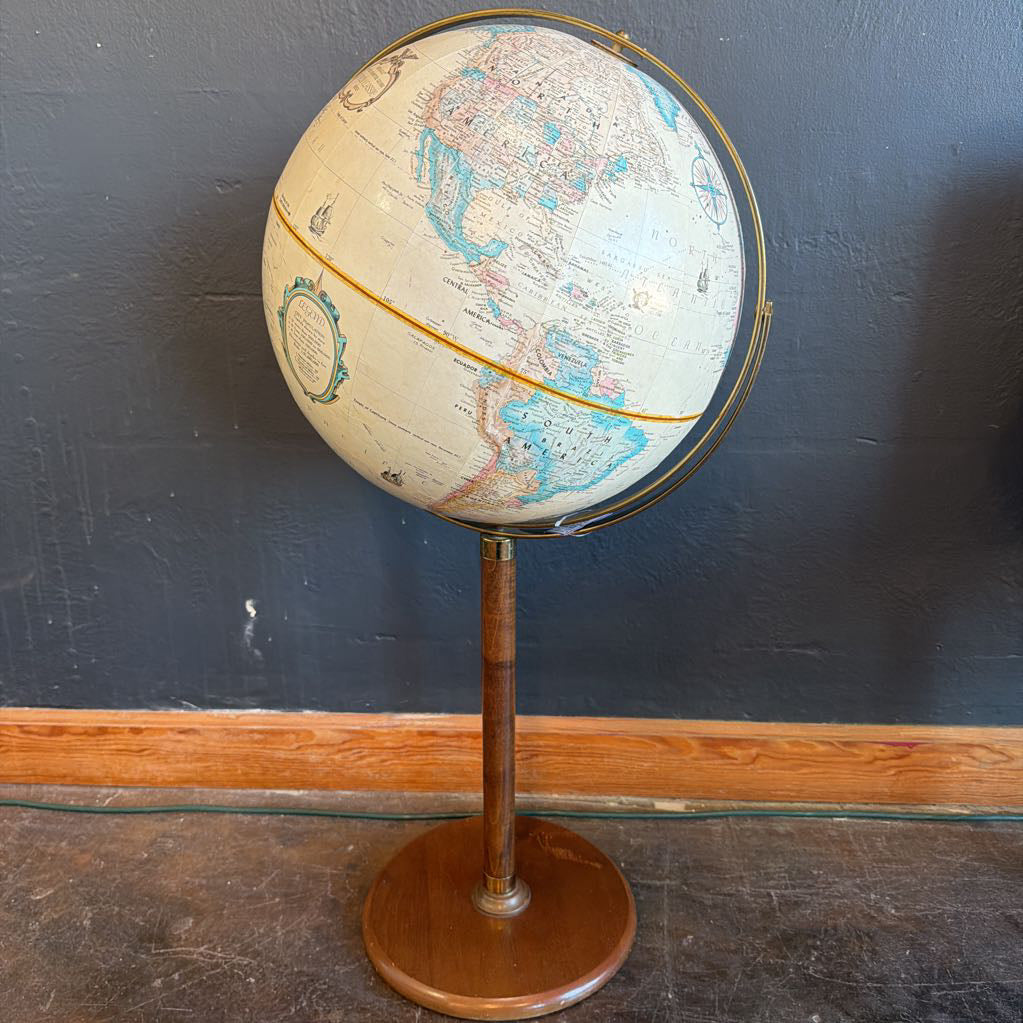 Vintage-style globe on a stand against a dark wall.