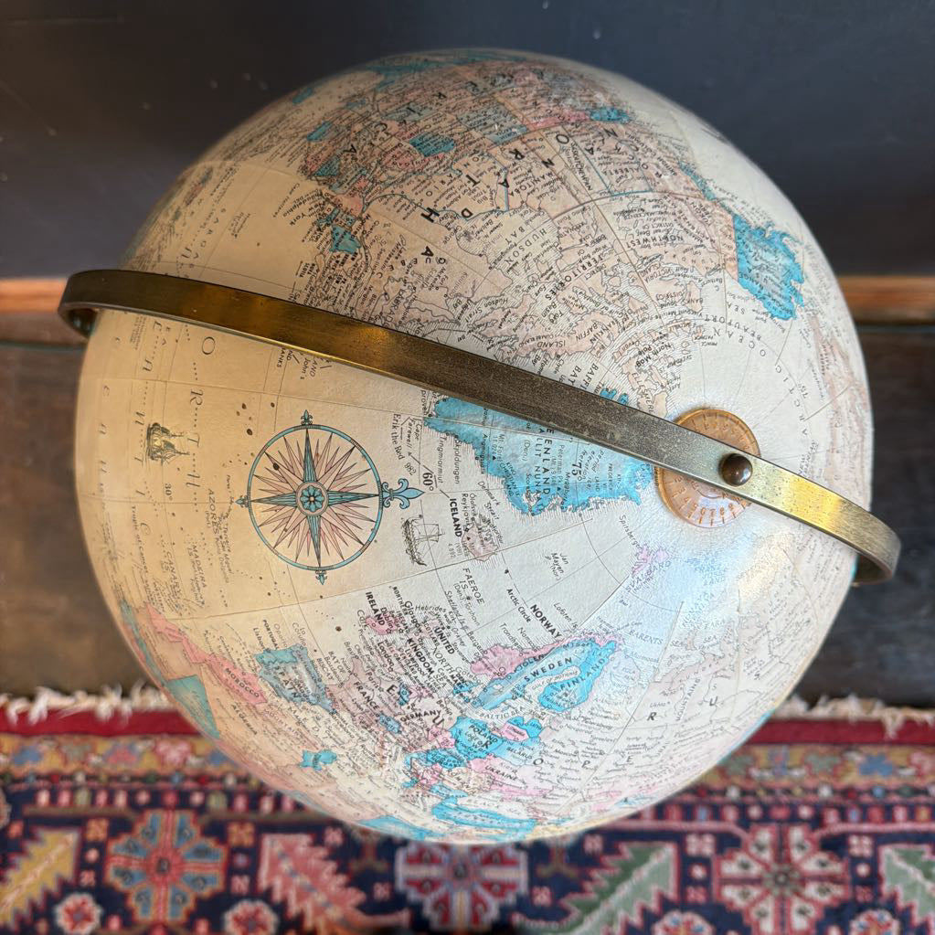 Vintage-style globe with a compass rose on a patterned surface