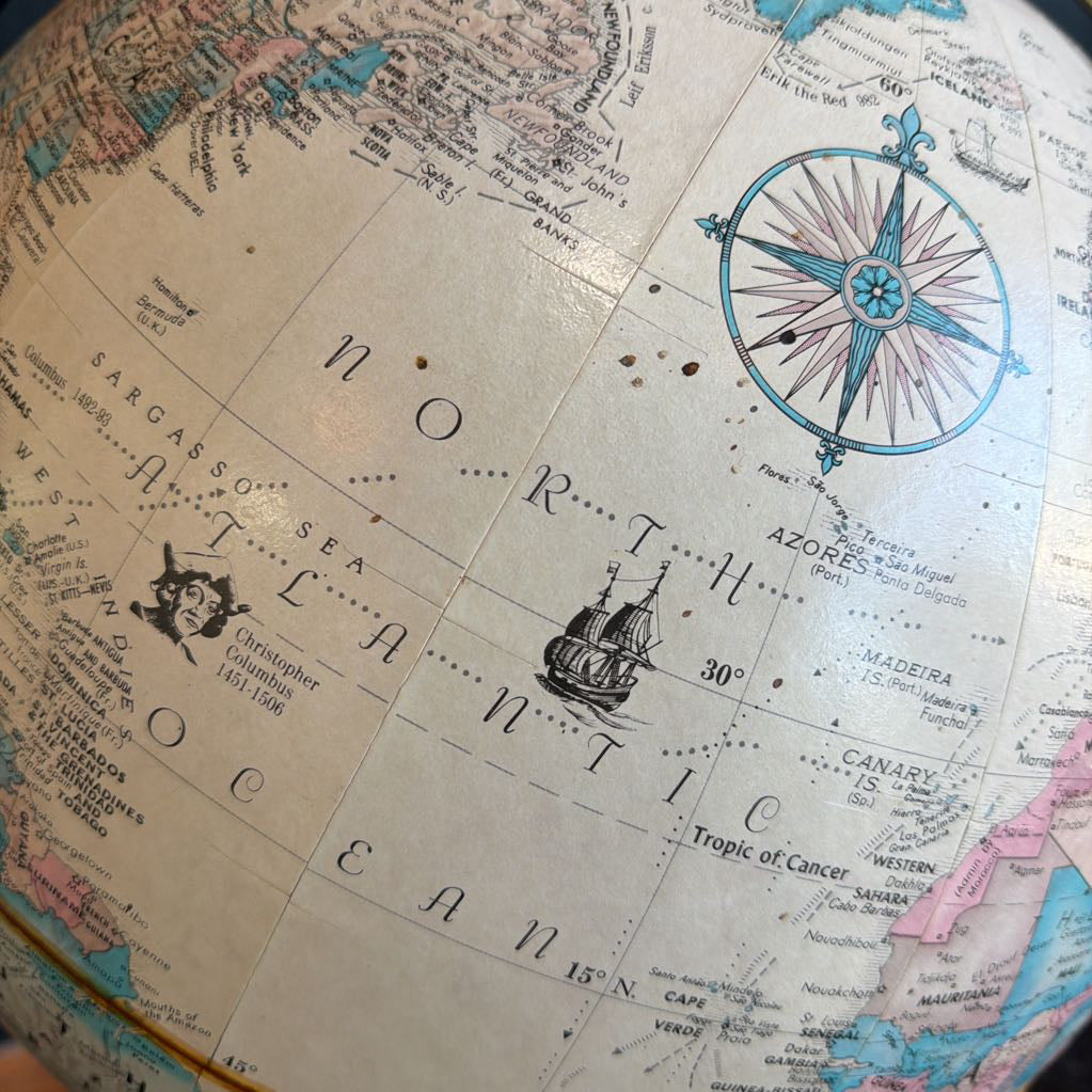 Close-up of a vintage-style world map with a compass rose and text.