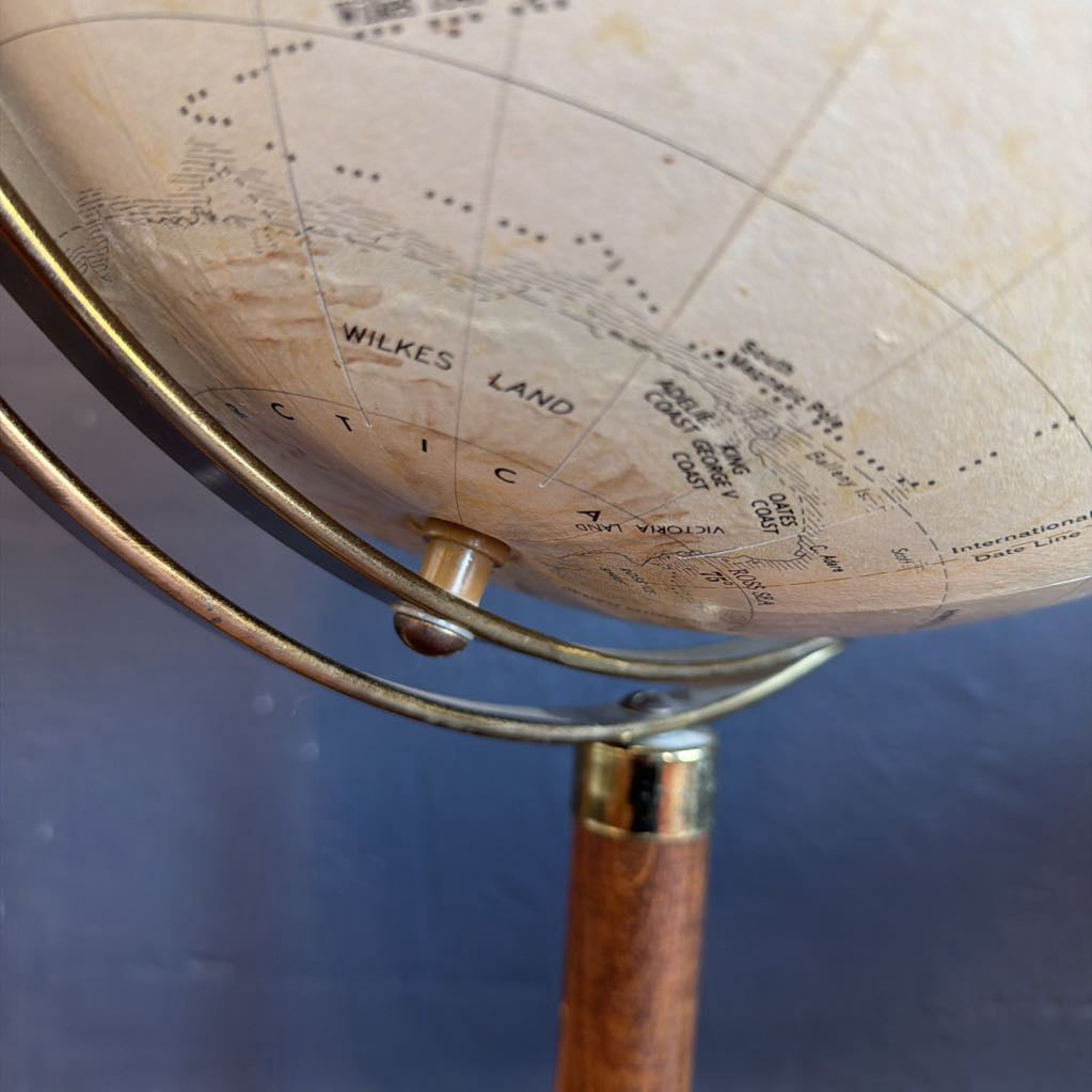 Close-up of a vintage-style globe with wooden stand on a blue background