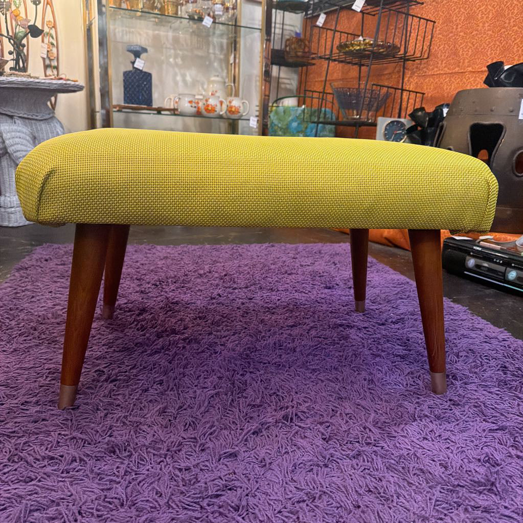 Yellow bench on a purple rug with a store interior background