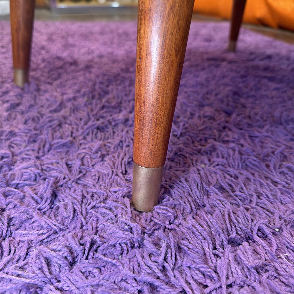 Wooden leg with a metal foot on a purple textured rug