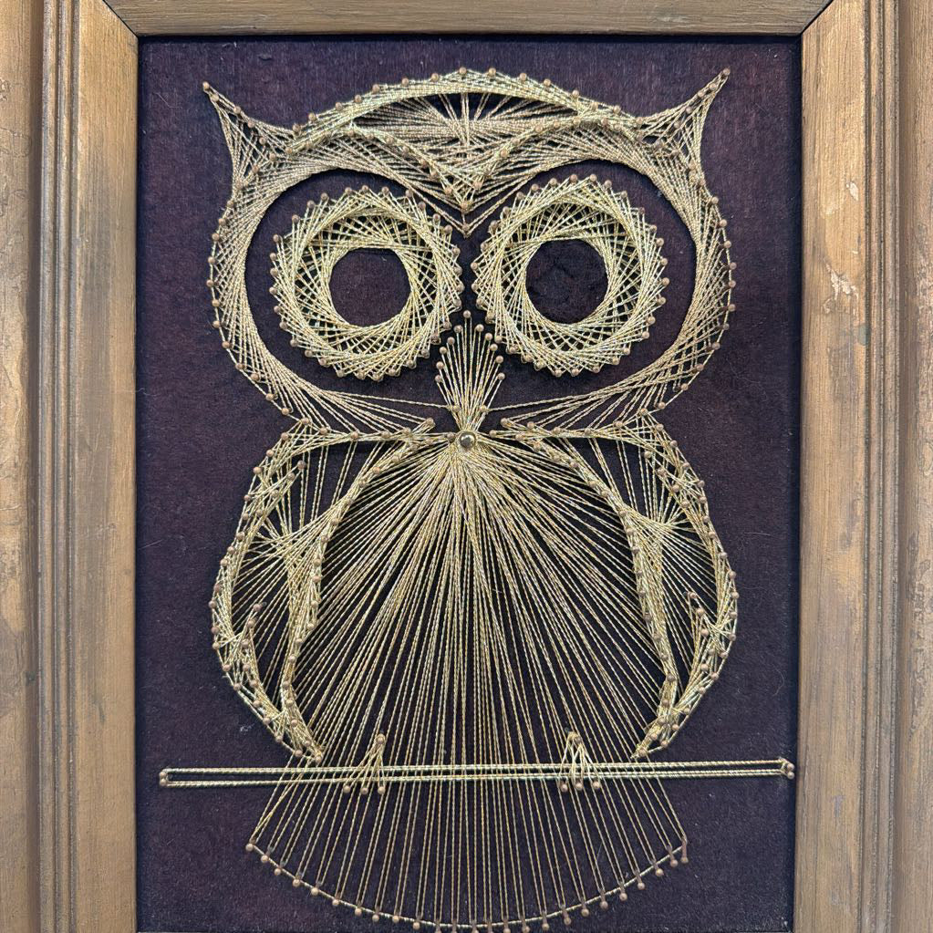 framed bronze owl string art against a dark brown fabric background