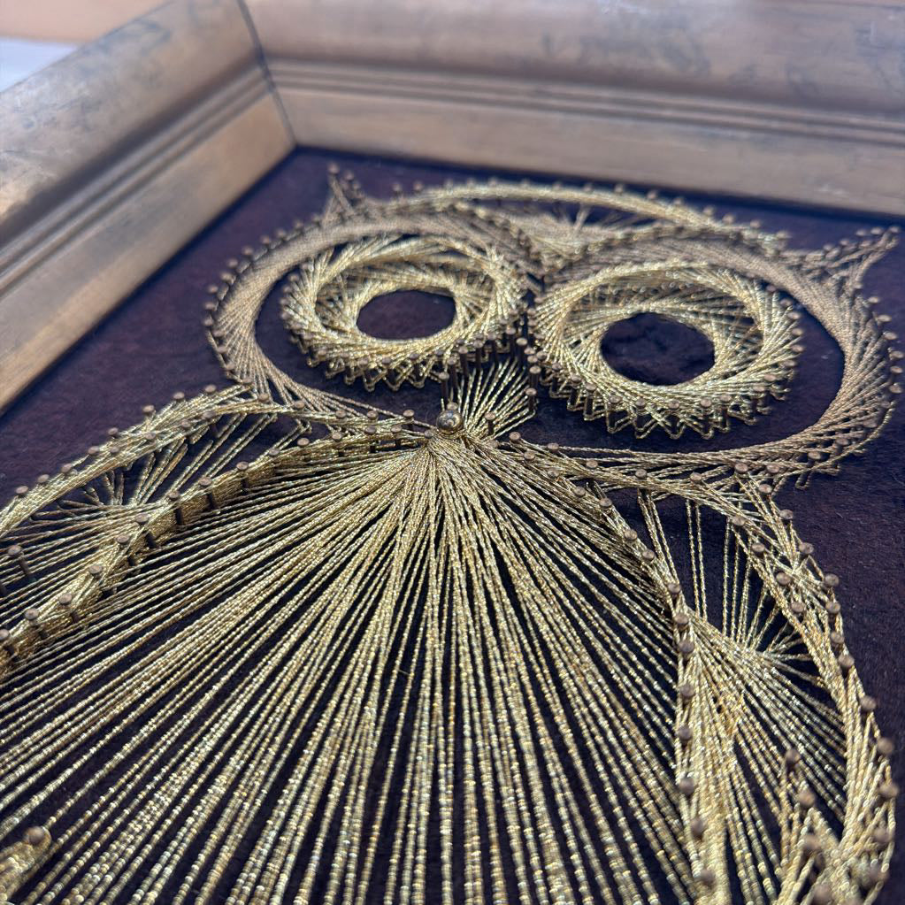 framed bronze owl string art against a dark brown fabric background