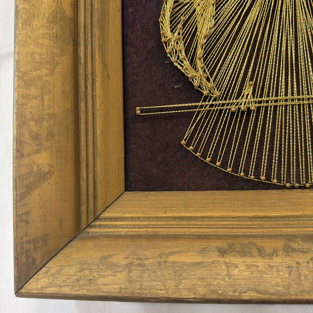 framed bronze owl string art against a dark brown fabric background