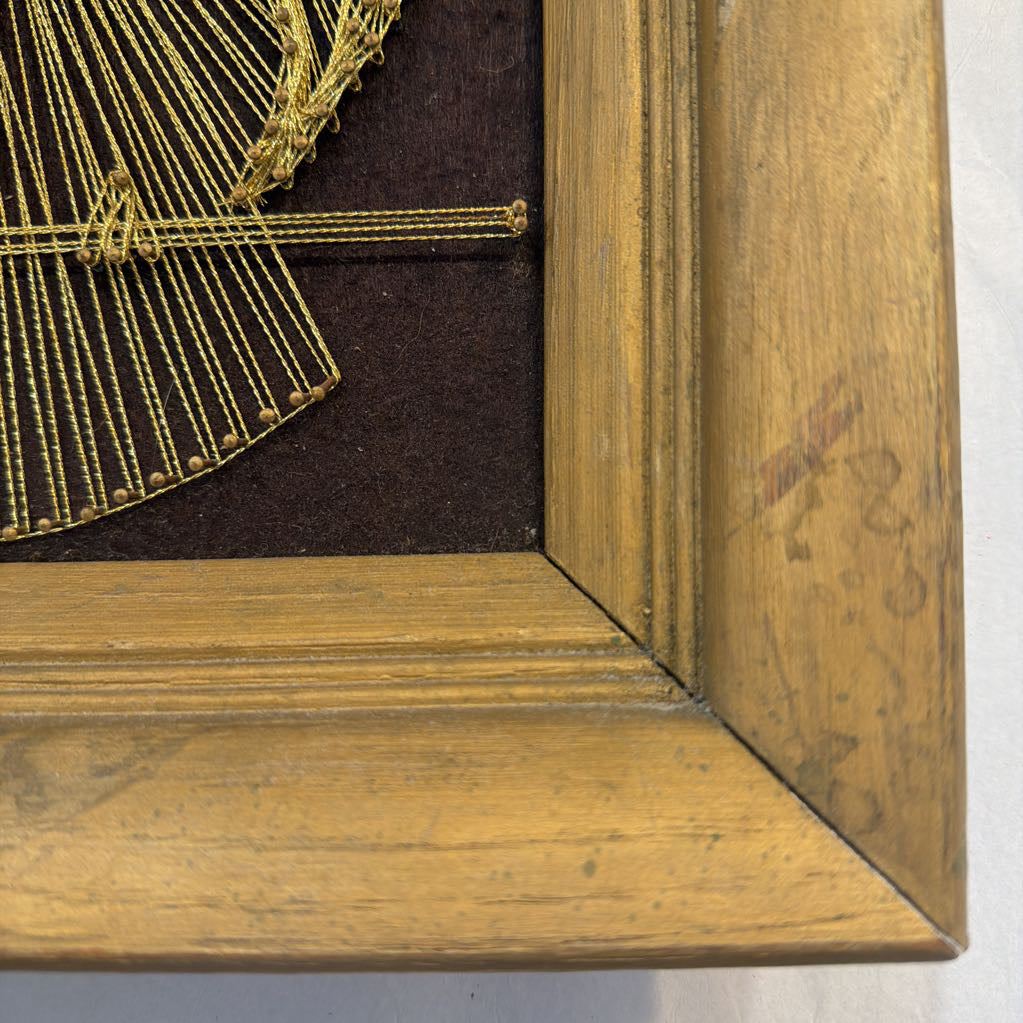 framed bronze owl string art against a dark brown fabric background