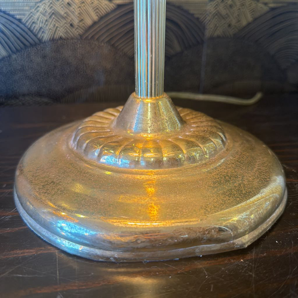 Close-up of a glass base with a metallic stem on a dark surface.