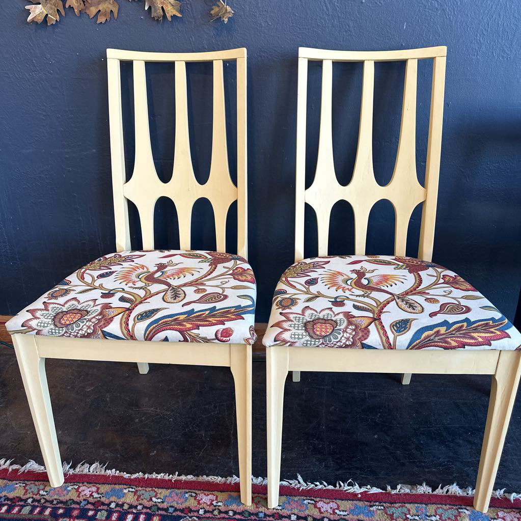 Two wooden chairs with patterned cushions against a blue wall.