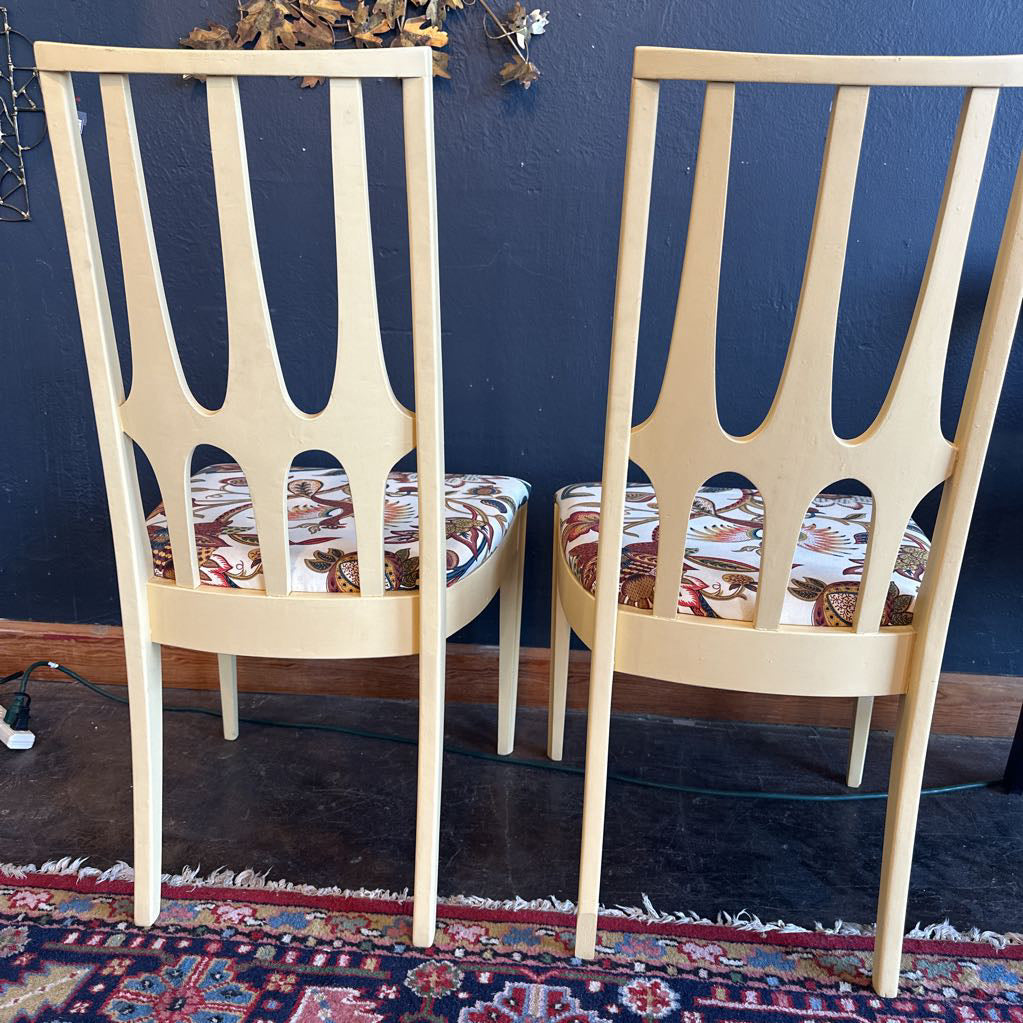 Two wooden chairs with patterned cushions against a blue wall.