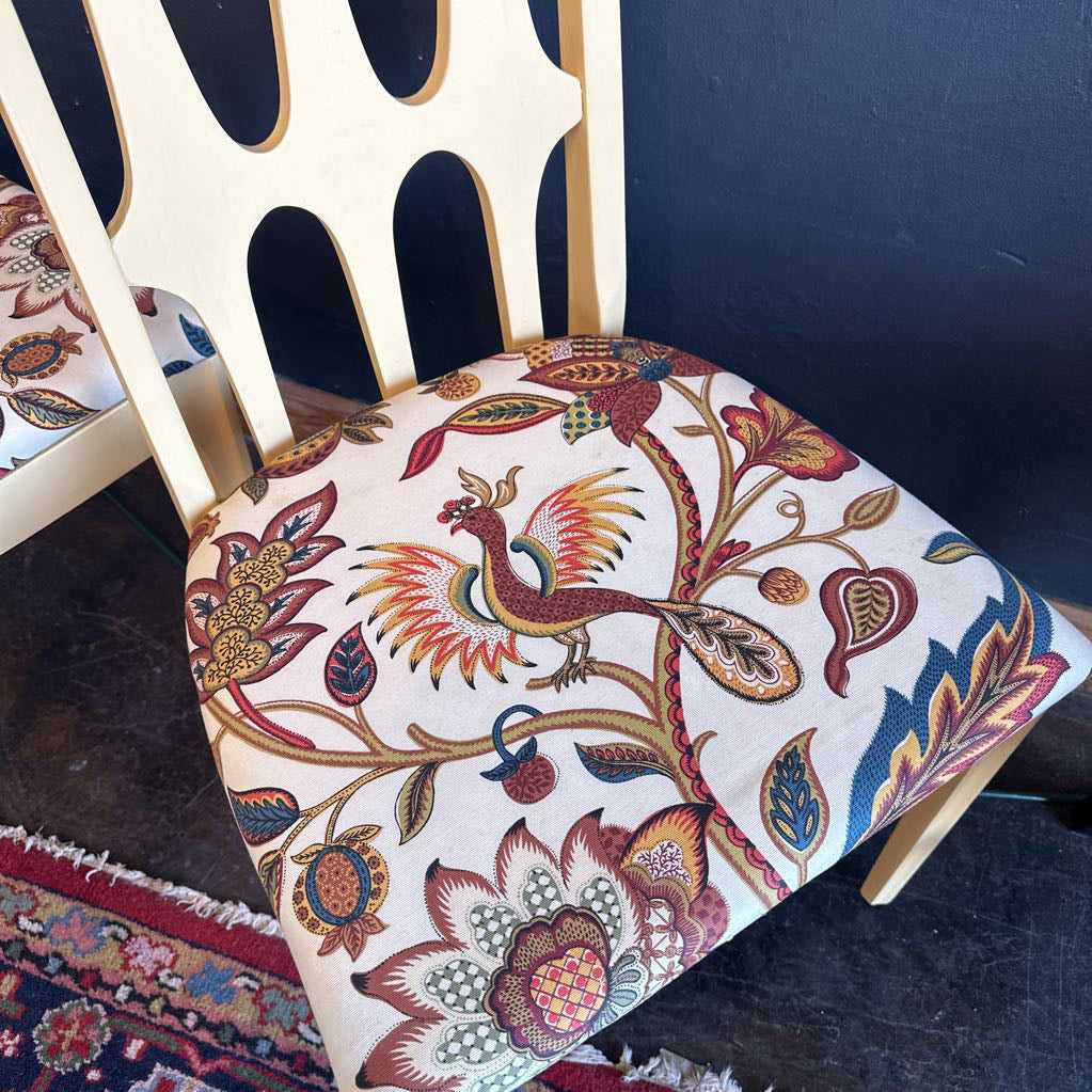 Decorative chair with a colorful peacock pattern on a dark blue wall background