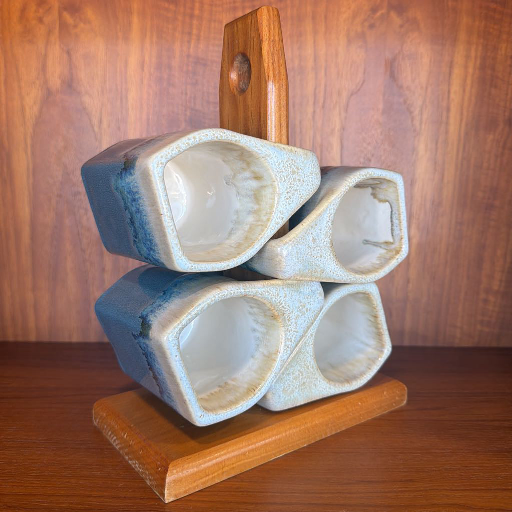 Ceramic vase with blue and white glaze on a wooden stand against a wooden background