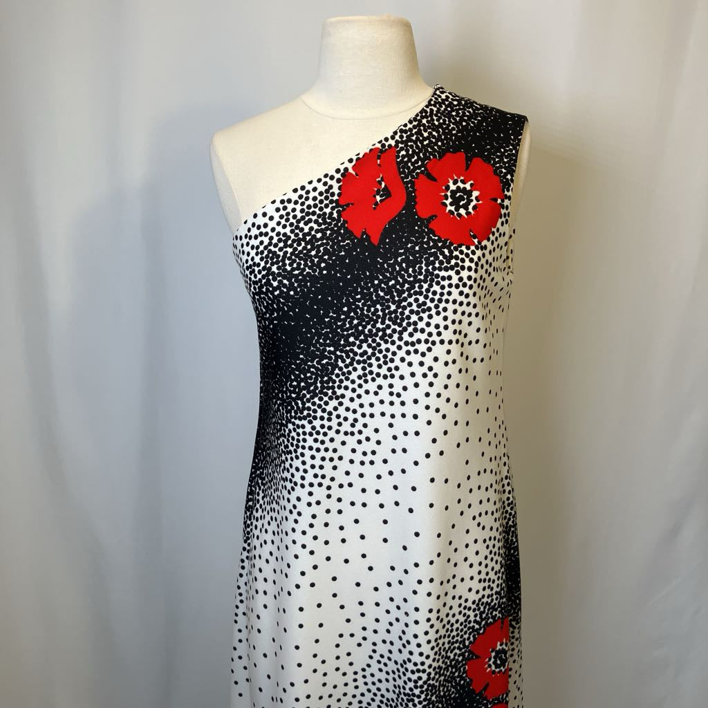 Mannequin wearing a black and white polka dot dress with red floral accents on a plain background