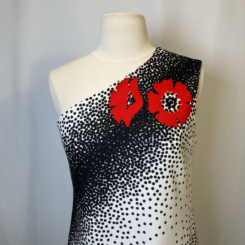 Mannequin wearing a black and white polka dot dress with red floral accents on a plain background