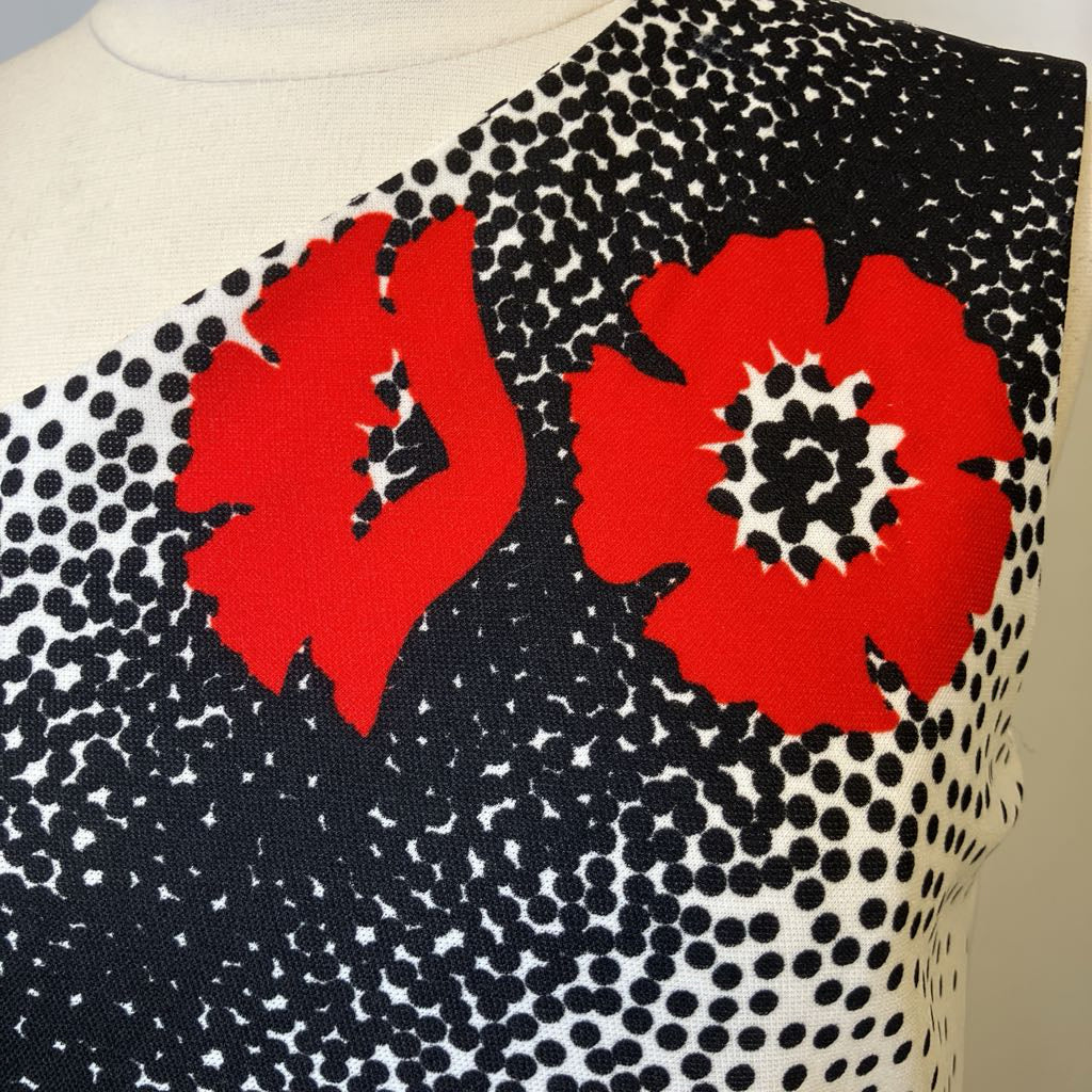 Black and white patterned fabric with red floral designs on a neutral background