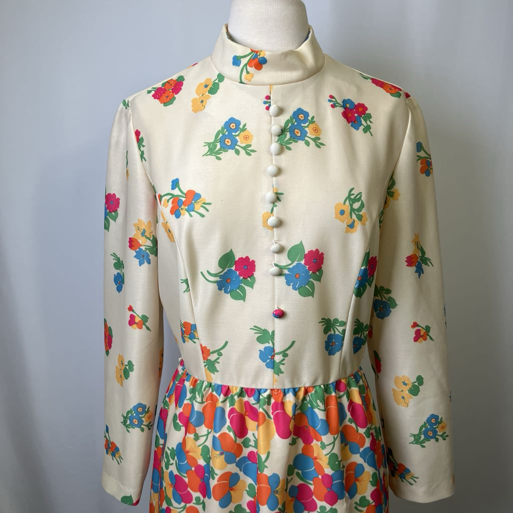 Mannequin wearing a cream-colored blouse with colorful floral patterns on a plain background