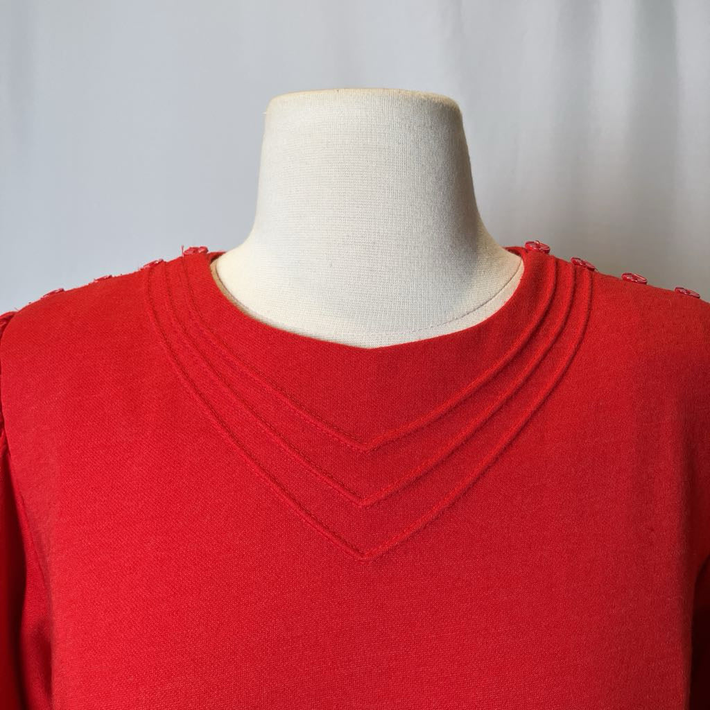 Red sweater on a mannequin against a plain background