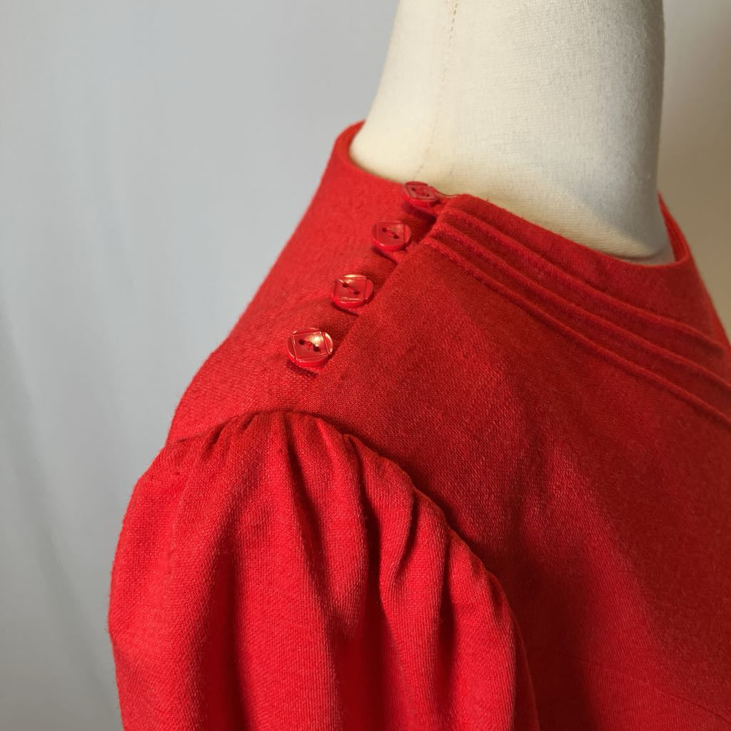Red garment with buttons on a mannequin against a gray background