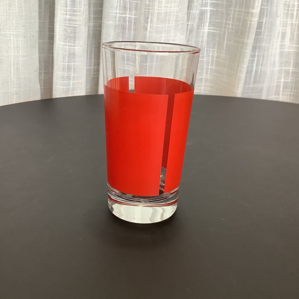 Clear glass with red interior on a dark surface and light curtain background