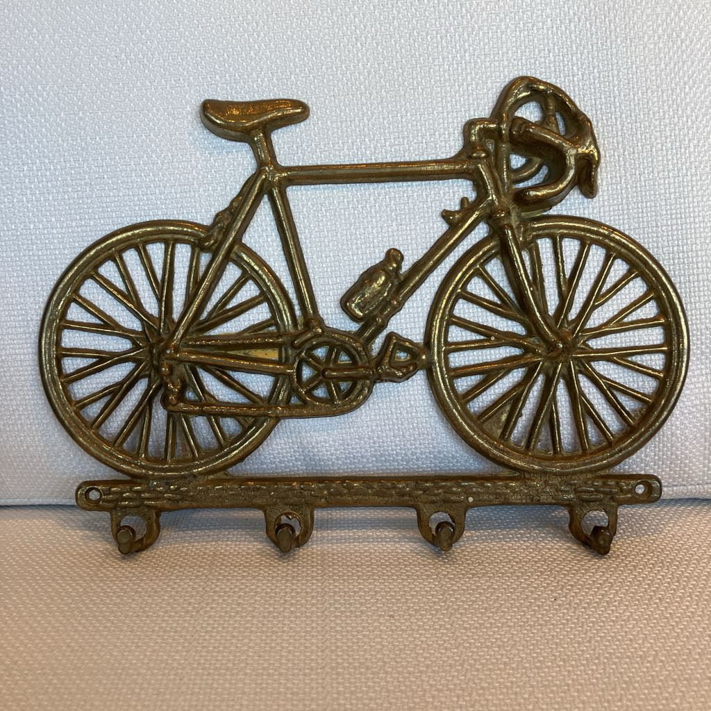Bronze bicycle-shaped wall hook on a light background