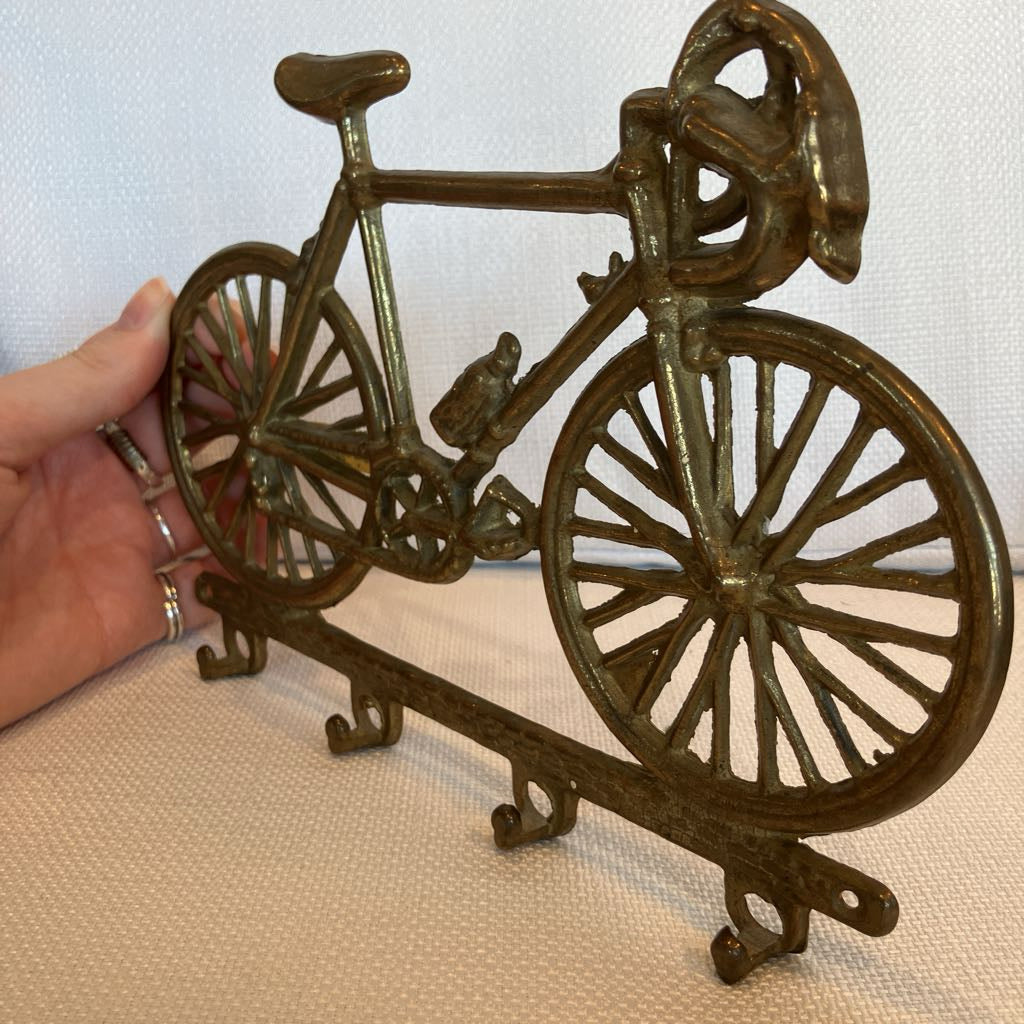 Bronze bicycle-shaped key holder on a beige surface